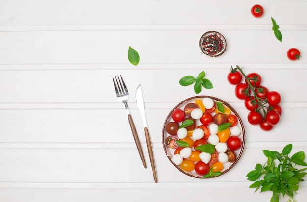 Tomate cereja mussarela bebê e salada de manjericão na vista superior de fundo branco