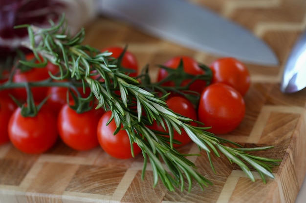 Tomate cereja orgânico com alecrim na placa de madeira com faca