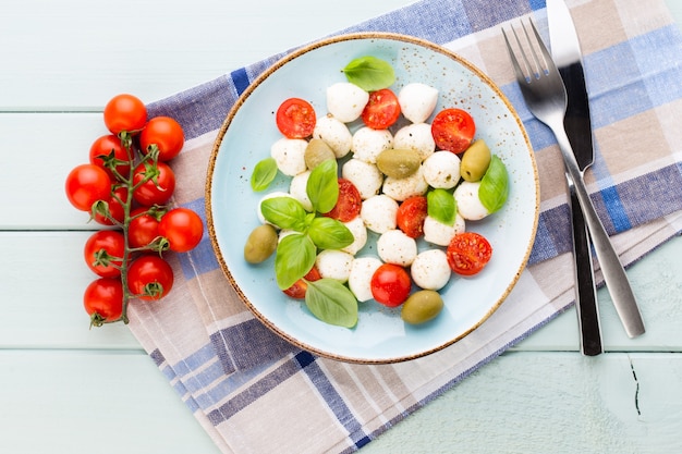 Tomate cereja, queijo mussarela, manjericão e especiarias no quadro-negro de pedra ardósia cinza. Ingredientes da salada caprese tradicional italiana. Comida mediterrânea.