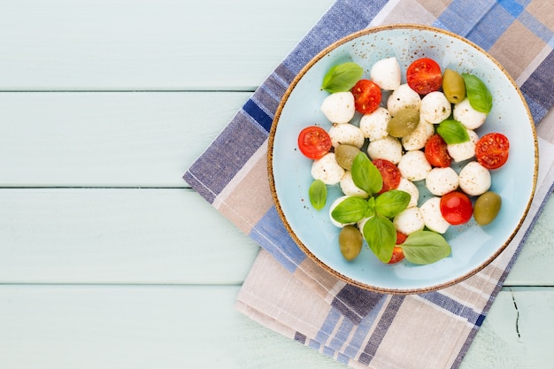 Tomate cereja, queijo mussarela, manjericão e especiarias no quadro-negro de pedra ardósia cinza. ingredientes da salada caprese tradicional italiana. comida mediterrânea.