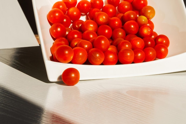 Tomate cereja. Tomate cereja em um prato branco. Luz dura. Luz brilhante e sombra.