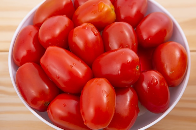 Tomate cereja. Tomate cereja na tigela de cerâmica no fundo de madeira