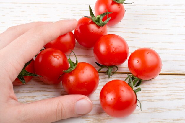 Tomate de cereza rojo y sabroso en la mano a la vista