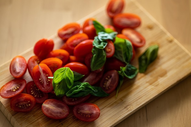 Tomate cherry y albahaca sobre fondo de madera Preparación de ensalada de verduras