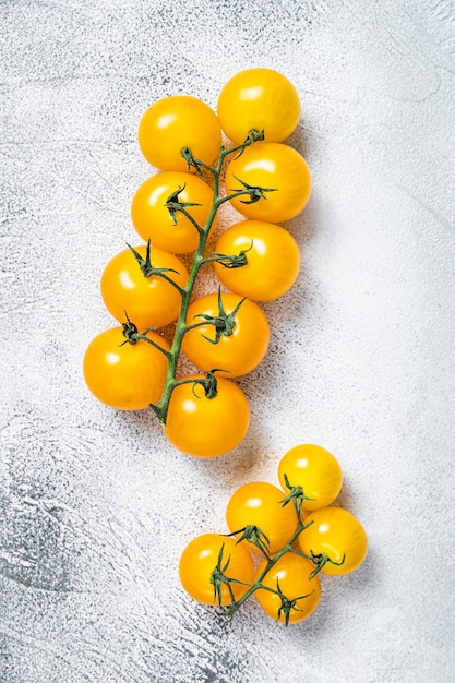 Tomate cherry amarillo pequeño en una mesa de cocina. Fondo blanco. Vista superior.