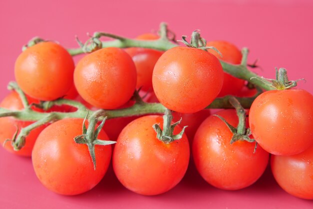 Tomate cherry de color rojo sobre fondo rojo.