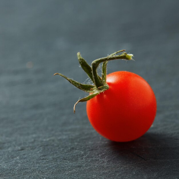 Tomate cherry fresco aislado en superficie negra