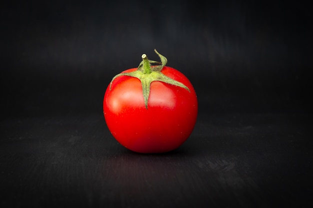 Tomate cherry rojo aislado en negro