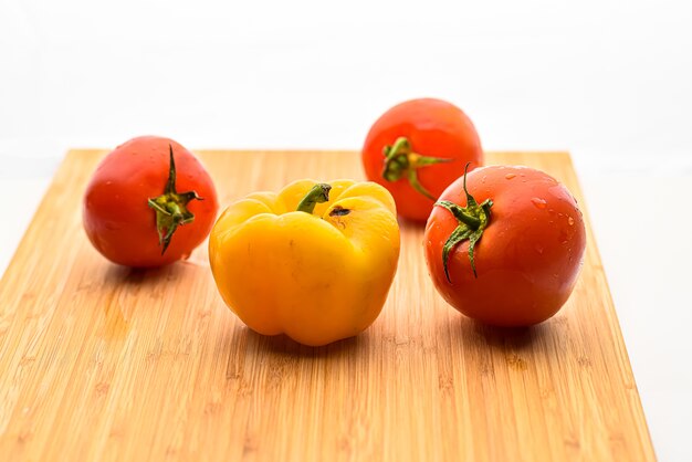 Tomate com pimentão amarelo na tábua de madeira