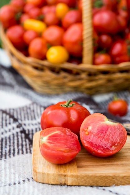 Un tomate cortado en una tabla. Recolección en otoño. En el contexto de una gran canasta de tomates.