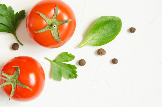 Tomate cru, ervas e pimenta preta sobre um fundo claro de concreto