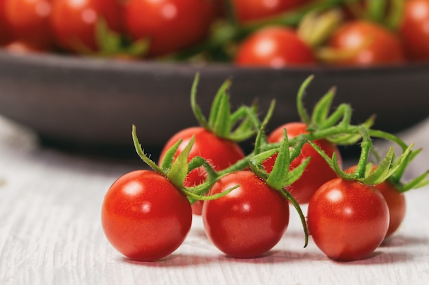 Tomate de cereja fresco na tabela de madeira branca.