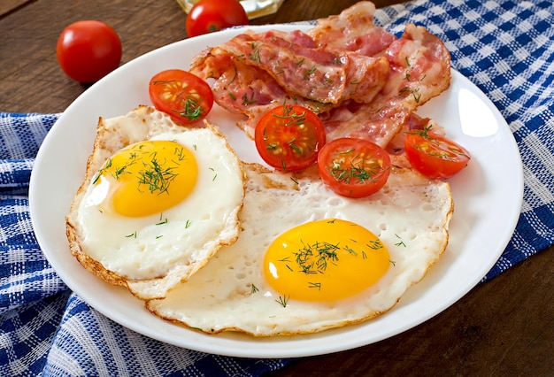 Tomate de pequeno-almoço inglês, bacon de ovo e vegetais em estilo rústico em fundo de madeira