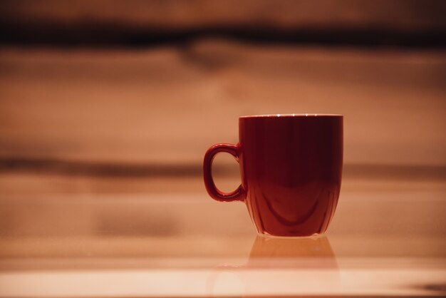 Tómate un descanso para tomar café. Primer plano de la taza de café en la mesa de cristal con fondo de madera