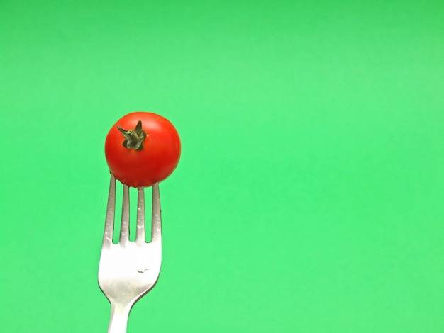 Foto tomate fresco en horquilla con fondo verde