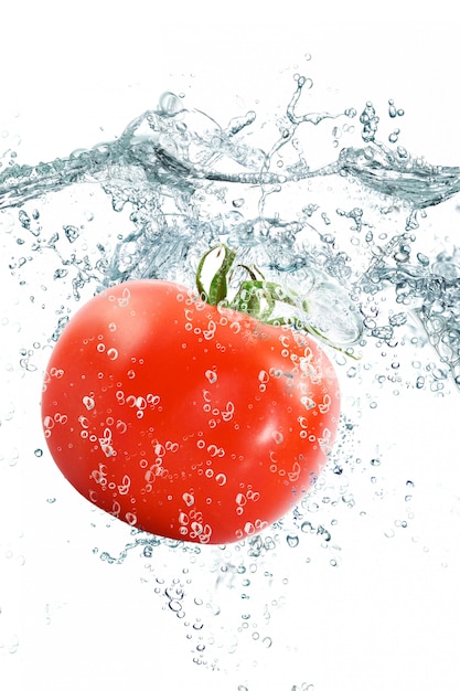 Tomate fresco que cae en el agua