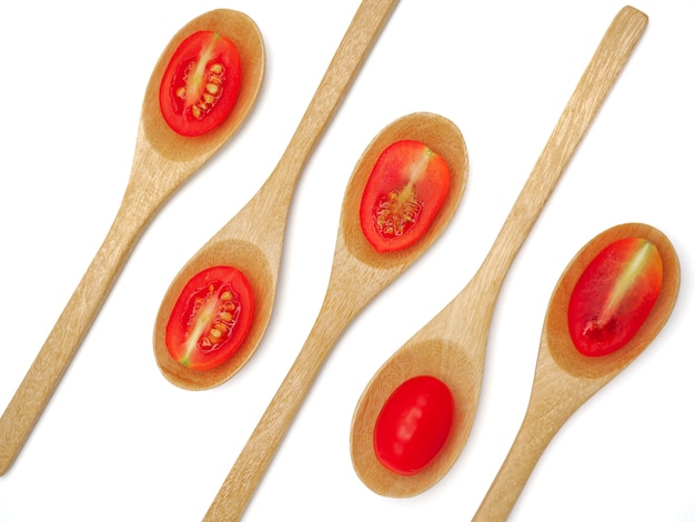 Tomate fresco de la uva o de cereza con la cuchara de madera en el fondo blanco.