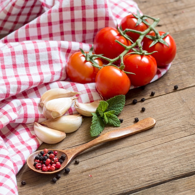 Tomate, hortelã, alho, pimenta e pano de prato em uma mesa de madeira fechar