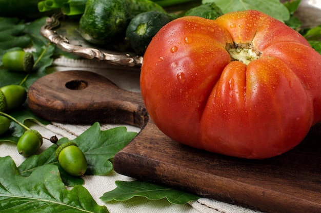 Tomate maduro e carnudo sobre fundo verde uma gota de água legumes de fazenda pepinos um estilo rústico