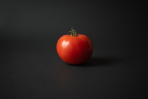 Tomate maduro rojo fresco sobre un fondo negro