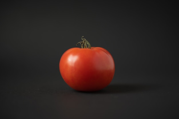 tomate maduro vermelho em um fundo preto escuro