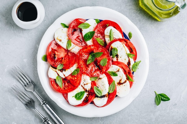 Tomate manjericão mussarela Salada Caprese com vinagre balsâmico e azeite Vista superior fundo de pedra cinza