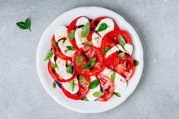 Tomate manjericão mussarela salada caprese com vinagre balsâmico e azeite vista superior fundo de pedra cinza