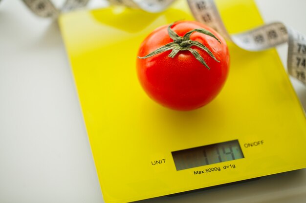 Tomate mit Maßband auf Waage