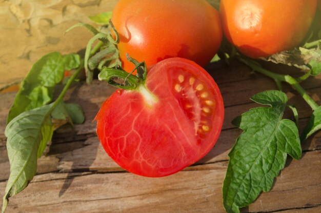 Tomate mit Scheibe auf rustikalem Holzhintergrund Frisch geschnittene Tomate auf Holztisch