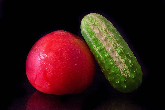 Tomate y pepino sobre un fondo negro