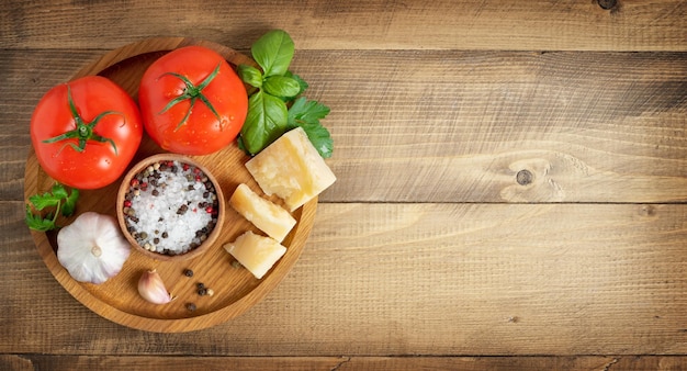 Tomate queijo parmesão e especiarias no espaço de cópia do conceito de comida italiana de fundo de madeira