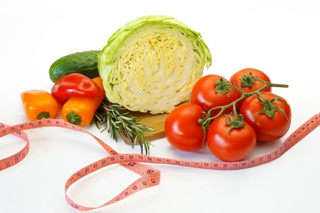 Tomate, repolho e pimentão, pepino e uma fita métrica em fundo branco
