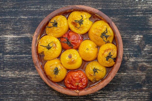 Tomate rojo y amarillo al horno. Tomates en una fuente para hornear sobre una mesa de madera. Un plato vegetariano sano y delicioso. De cerca, vista superior