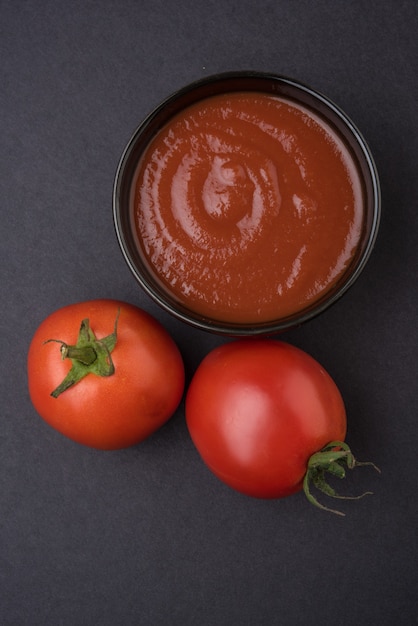 Tomate rojo fresco de la granja con pasta o puré en un recipiente de cerámica. Enfoque selectivo