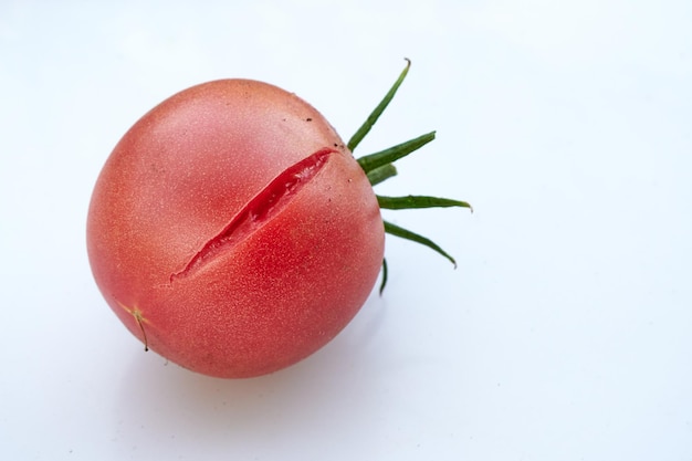 Tomate rojo jugoso agrietado sobre fondo blanco