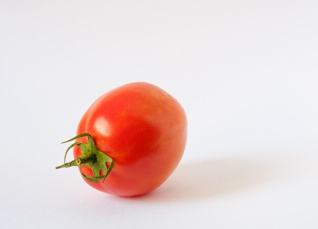 Un tomate rojo sobre fondo blanco.