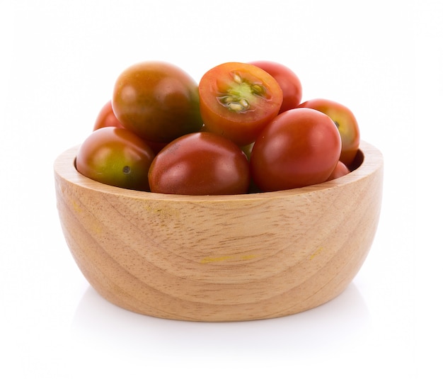 Tomate en un tazón de madera sobre fondo blanco