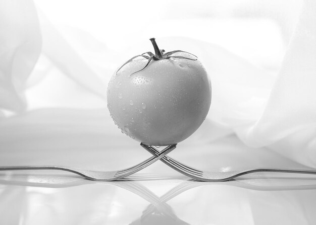 Foto tomate en el tenedor negro blanco