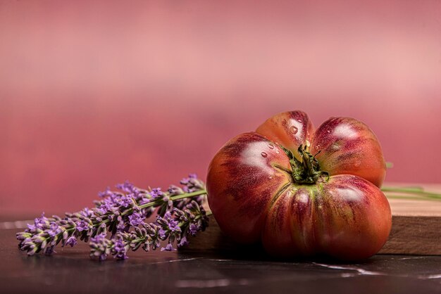 Tomate tigre en una tabla de cortar con hojas de albahaca sobre fondo de madera Espacio de copia Tomate fresco para cocinar Tomate con gotas de agua