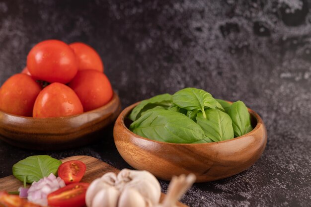 Foto tomate y tomate en una taza de madera con ajo en una tabla de cortar de madera