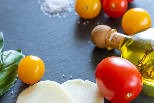 Foto tomate vermelho e amarelo, queijo mussarela, azeite e manjericão verde