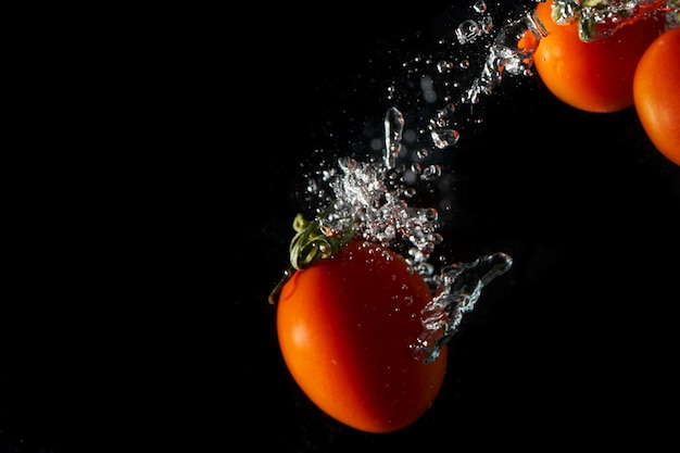 Tomate vermelho em fundo preto com respingos de água