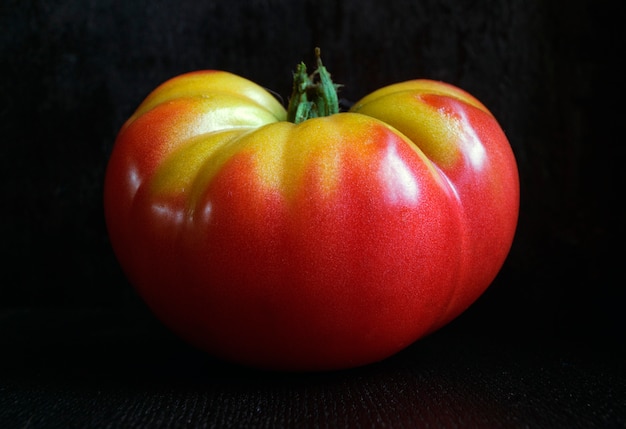 Tomate vermelho maduro em um fundo preto