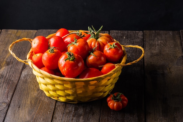 Tomaten aus einem Gemüsegarten in einem Weidenkorb auf einem Holztisch