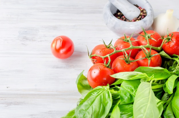 Tomaten, grünes Basilikum und Gewürze in einem Steinmörser,