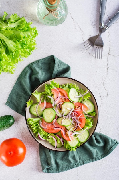 Tomaten-Gurken-Zwiebel-Kopfsalat-Salat auf einem Teller Vegetarisches Essen Ansicht von oben und vertikal