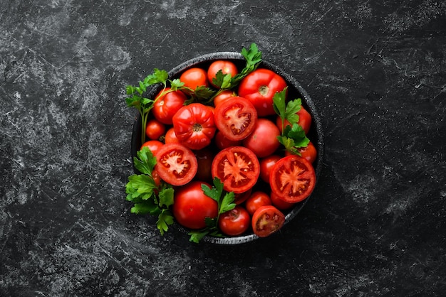 Tomaten in einem Teller auf schwarzem Stein Hintergrund Gemüse Draufsicht Freier Platz für Ihren Text