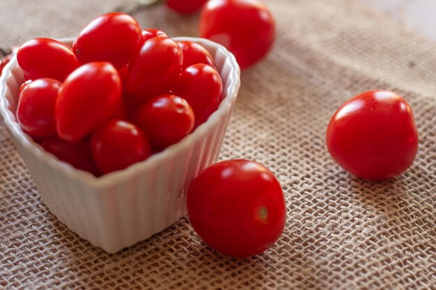 Tomaten in einer weißen Schüssel und weiter auf einem Strohtisch