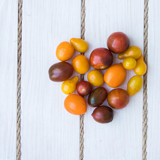 Tomaten in Herzform. weißer Holzhintergrund. Weicher Fokus. Ansicht von oben