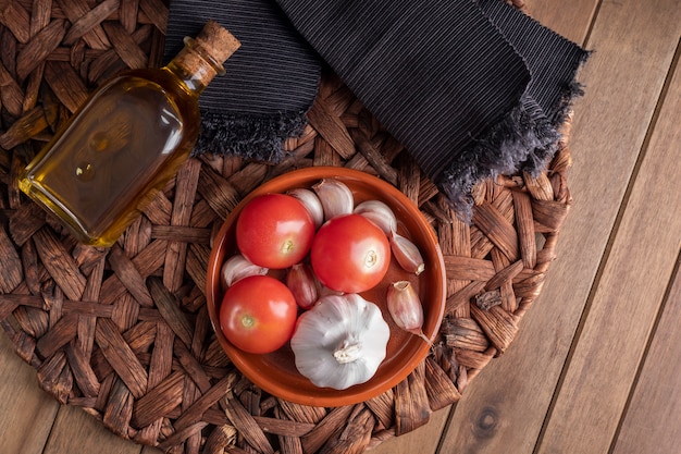 Tomaten, Knoblauch und extra Olivenöl auf rustikalem Holztisch.